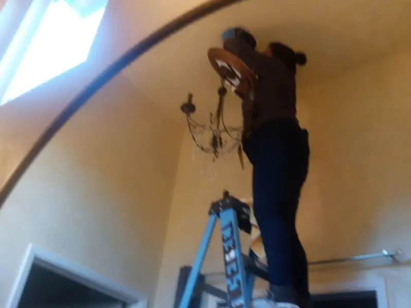 Electrician installing a chandelier in a Brookville residence